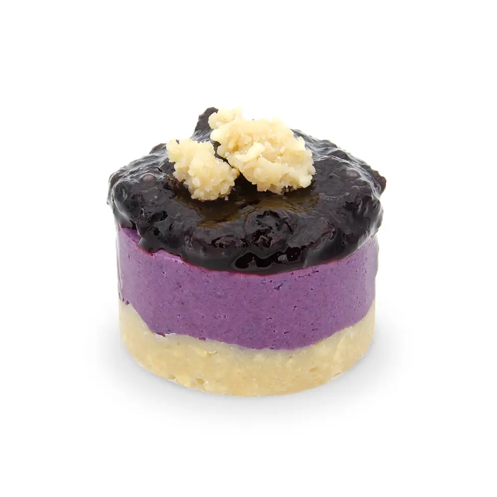 Pastel vegano de arándanos, con una base de frutos secos, una mousse violeta de arándanos, y encima una mermelada de arándanos